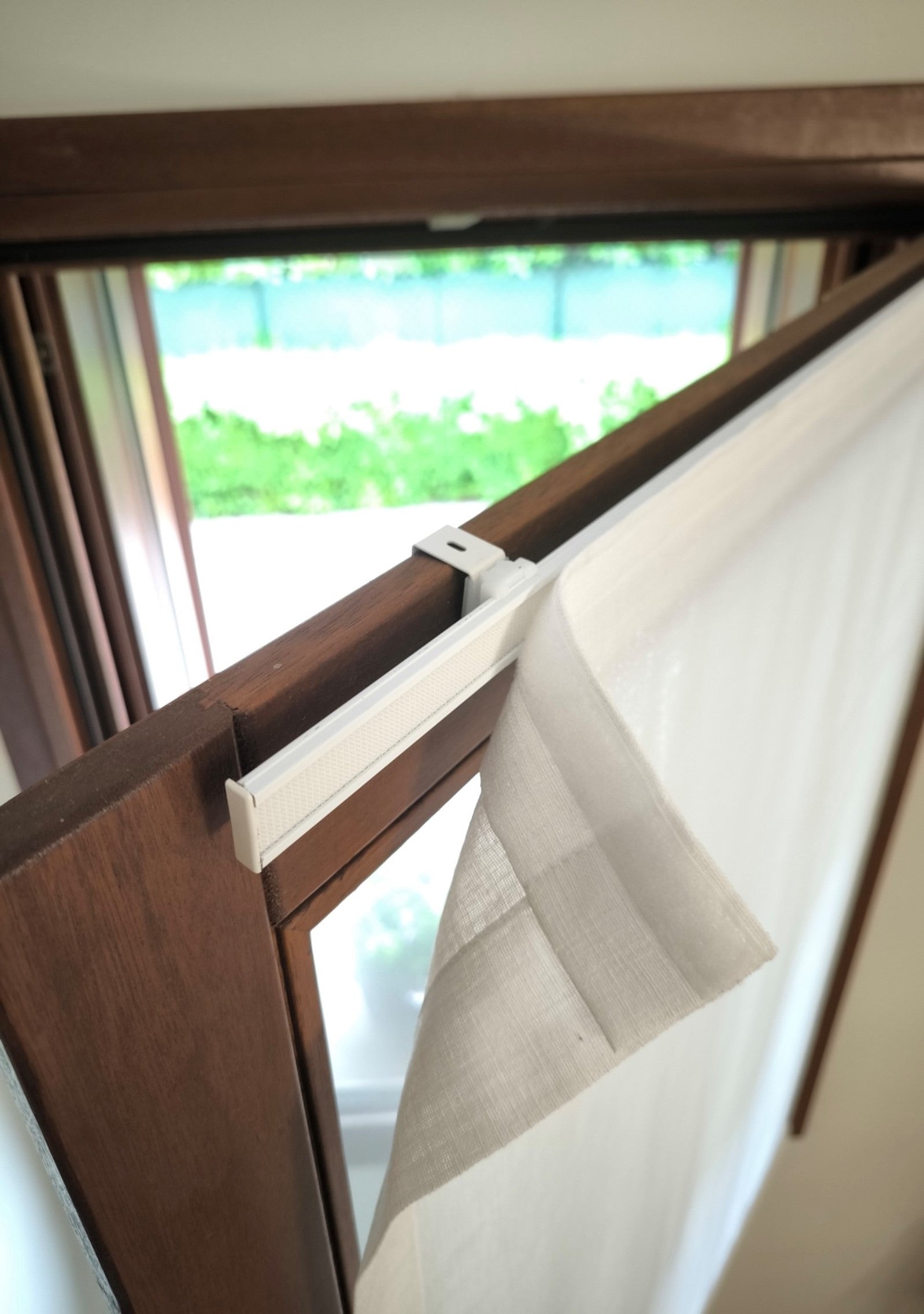 Tenda a vetro con velcro applicata a profilo in alluminio velcrato, montato con supporti a gancio senza fori sopra l’anta di una finestra in PVC