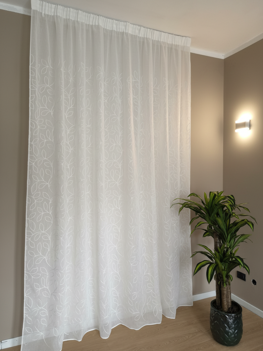 Tenda bianca con ricamo a foglia appesa a un binario