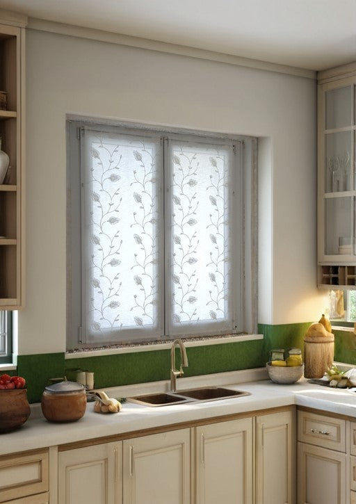 Coppia di tende bianche con ricamo floreale su una finestra di una cucina