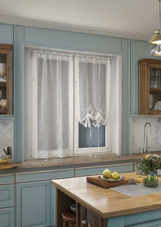 Una cucina con una finestra sulla quale sono installate due tende regolabili in altezza, una su ciascuna parte della finestra. Le tende sono leggermente abbassate, permettendo alla luce naturale di entrare nella stanza.