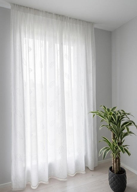 Tenda bianca su binario con tessuto naturale bianco, decorata con ricami tono su tono raffiguranti foglie cadenti.