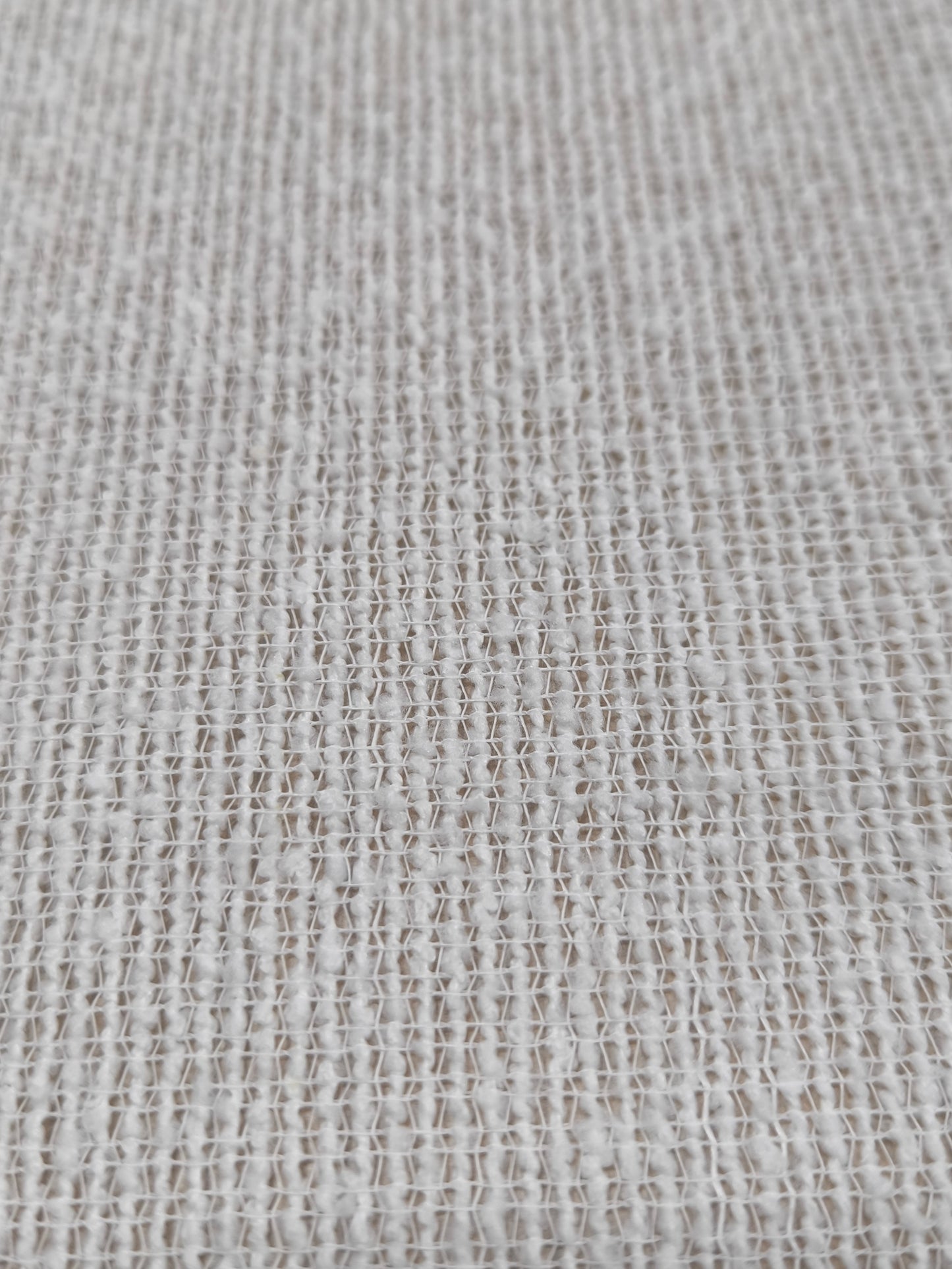 Primo piano del tessuto bouclé con superficie a riccioli, che mostra la texture morbida e irregolare.