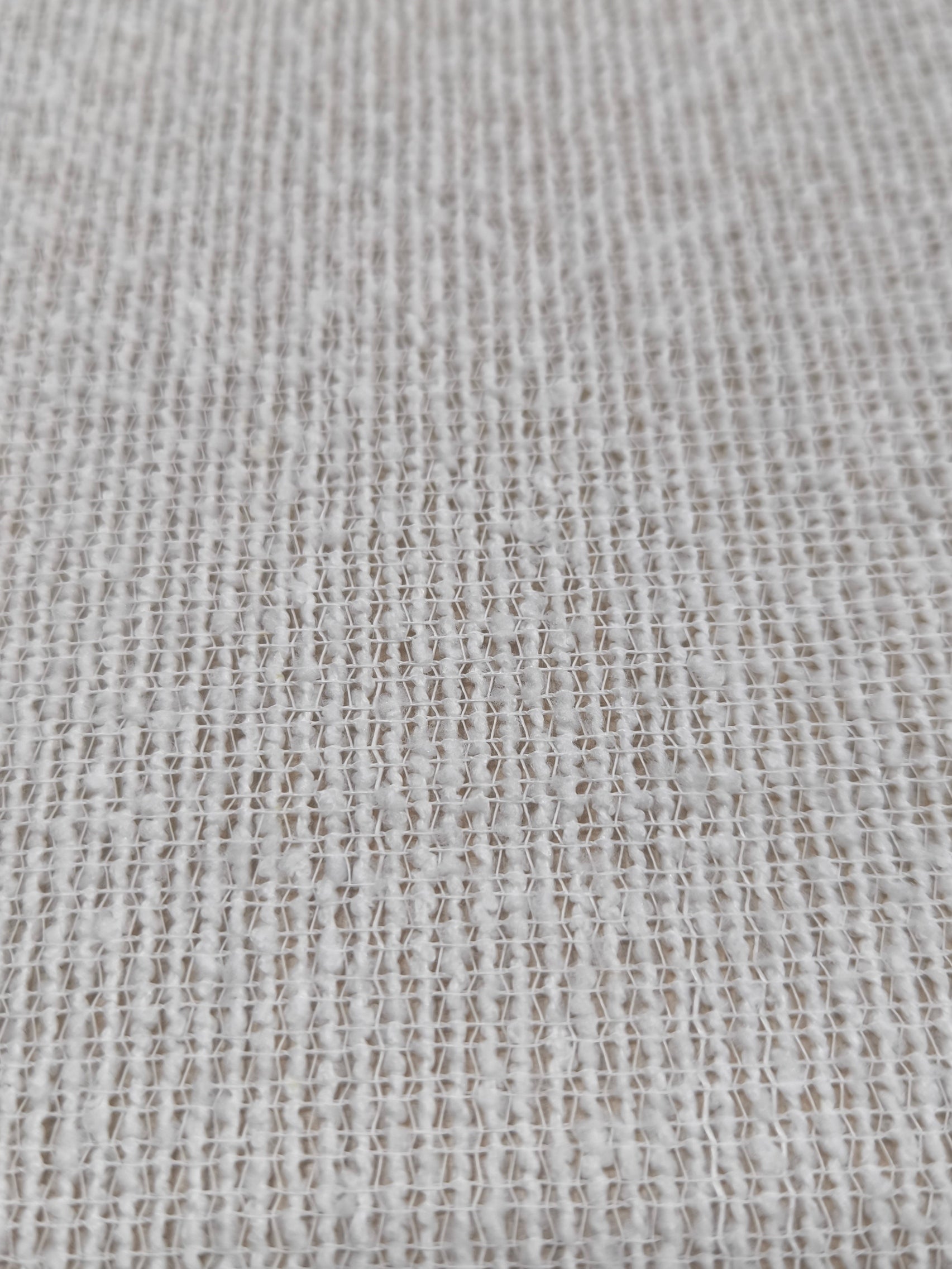 Primo piano del tessuto bouclé con superficie a riccioli, che mostra la texture morbida e irregolare.